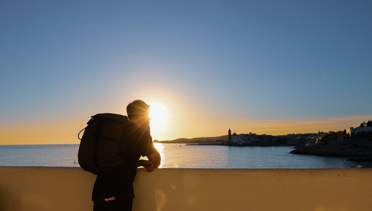 A man looking out over the sea at sunset